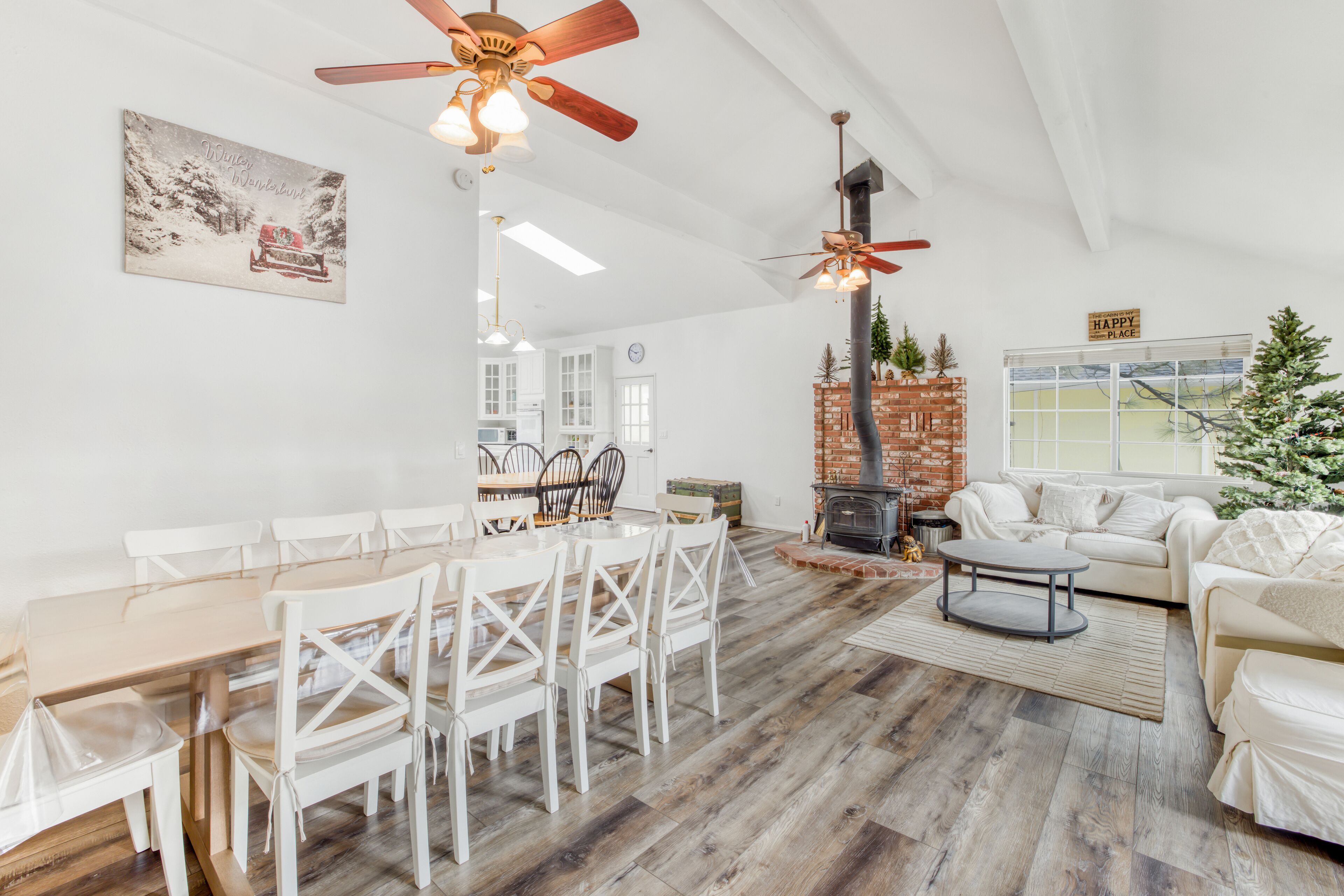 Un amplio salón con mesa de comedor, sillas blancas, chimenea y un árbol de Navidad.