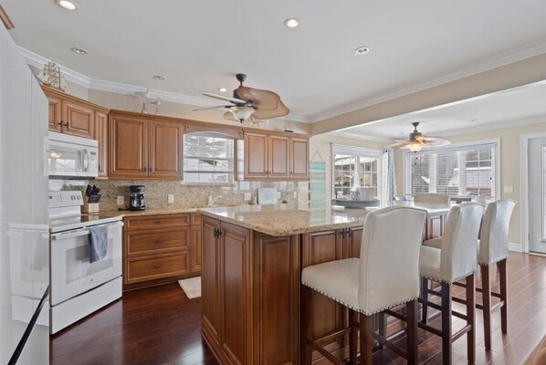 A spacious kitchen with wooden cabinets, a central island, and bar stools.