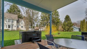 Eine überdachte Terrasse mit Grill, Sitzgelegenheiten und Blick auf eine Wohngegend.