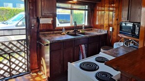 A compact kitchen with wooden cabinets, a white stove, a sink, and a microwave. - Rustic Retreat Cottage sleeps 6 with a lake view! (Worth Township)