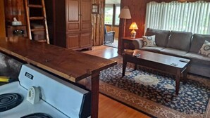 A cozy living room with a wooden coffee table, a sofa, and a lamp. - Rustic Retreat Cottage sleeps 6 with a lake view! (Worth Township)
