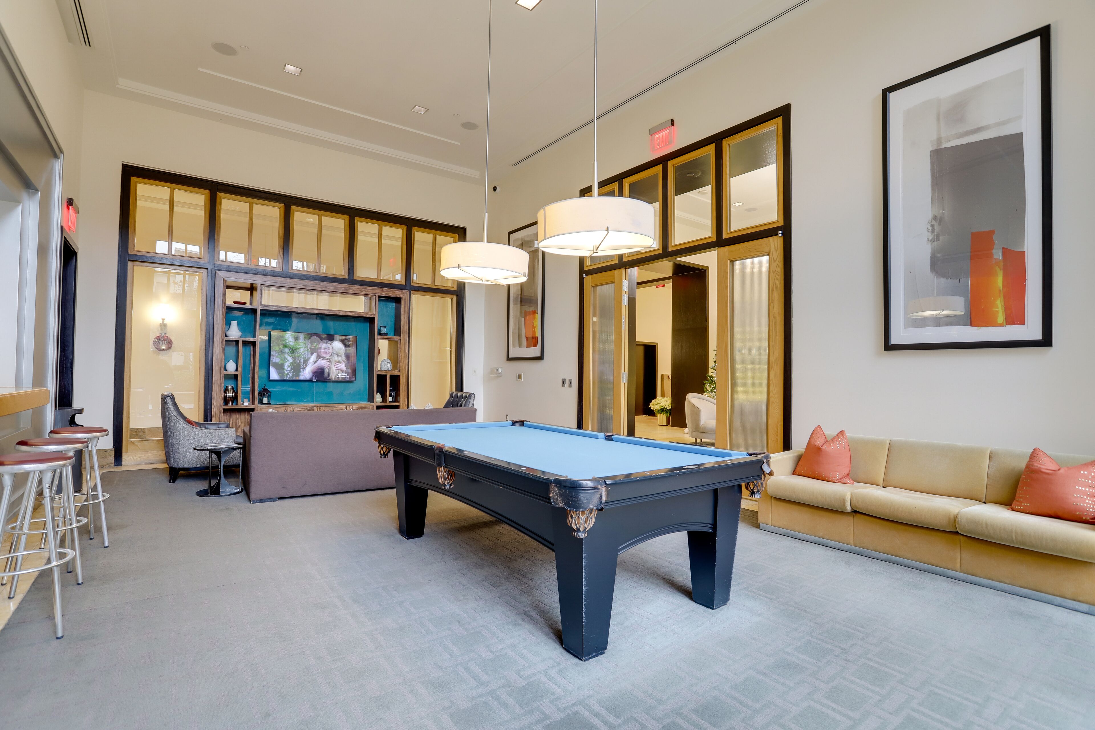 Une table de billard dans une pièce spacieuse, avec un canapé et des tabourets de bar.