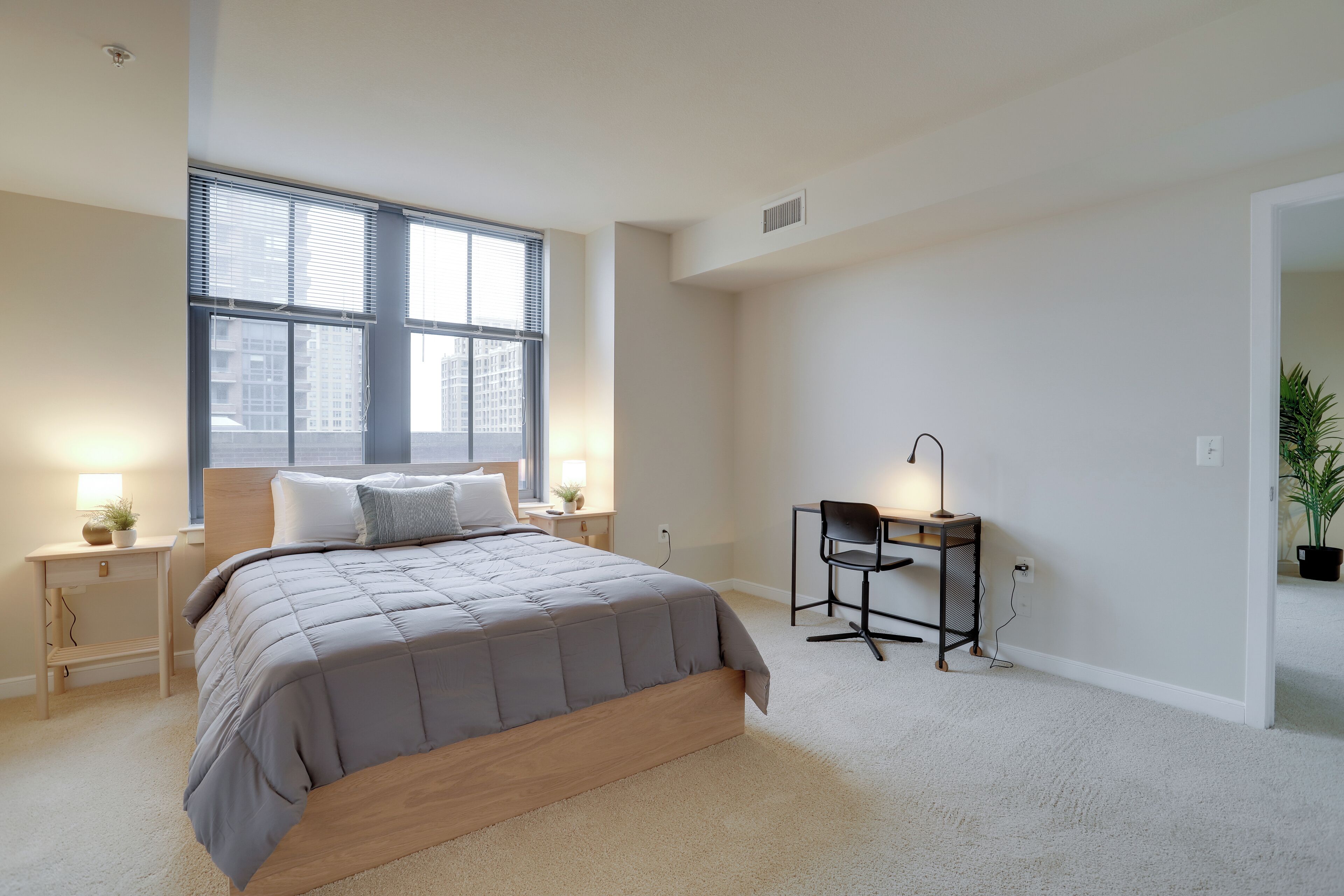 Une chambre à coucher comprenant un lit, des tables de chevet, un bureau et une chaise.