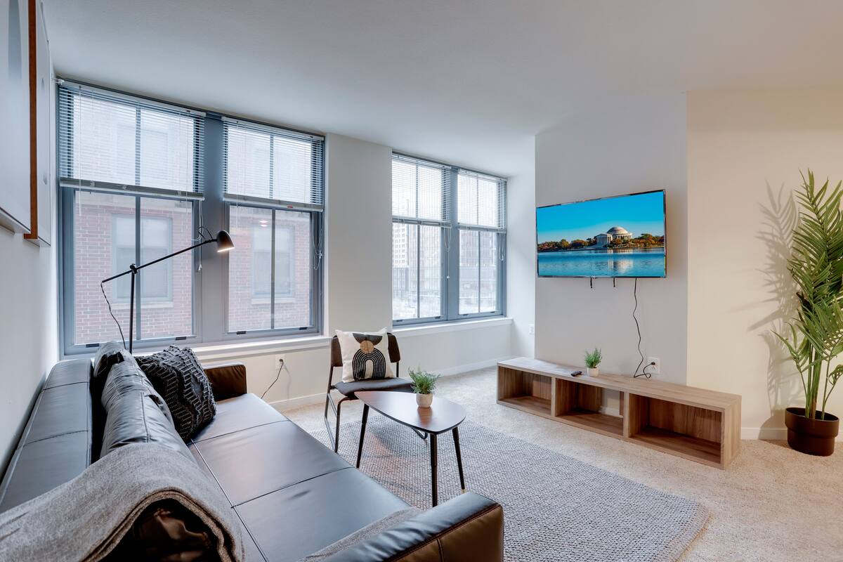 Ein modernes Wohnzimmer mit einer Couch, einem Couchtisch und einem an der Wand befestigten Fernseher.