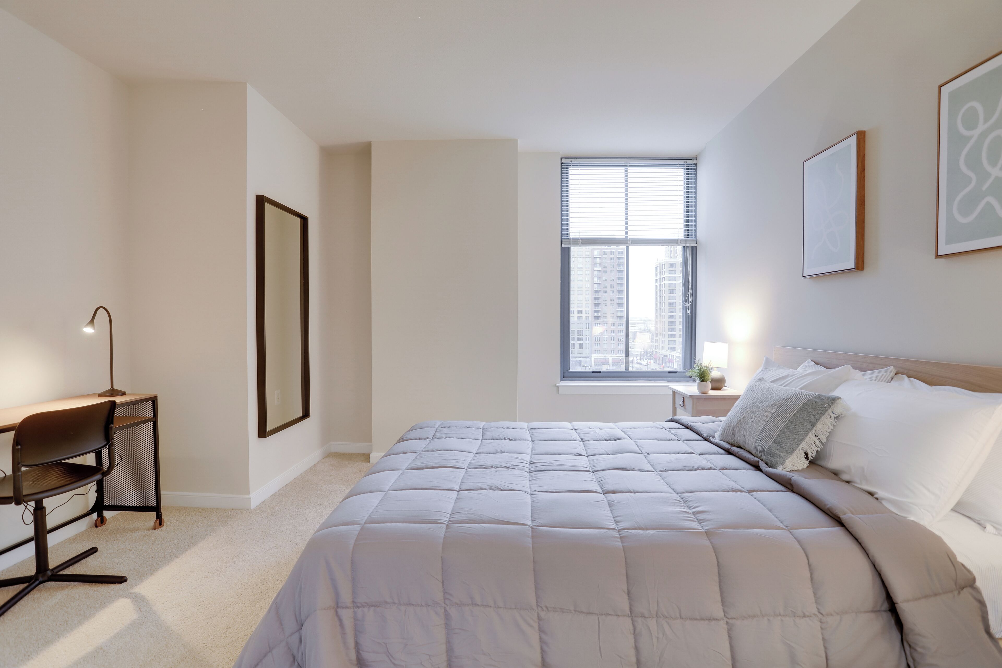 A bedroom with a bed, a desk, and a window.