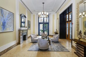 Eine geräumige Lobby mit einem prächtigen Kronleuchter, einem Kamin und einer Sitzecke mit drei Sesseln und einem Couchtisch.