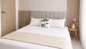 A modern hotel room with a large bed, a wooden door, a textured wall, and a small table with a vase. - Breathe in a quiet and safe forest  (Cali)