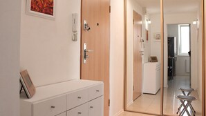A modern bedroom with a wooden wardrobe, a bedside table, and a large mirror. - Small one room apartment with balcony (Humenné)