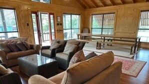Un vaste espace de vie doté d’un plancher en bois, d’un ensemble de canapés et d’une table basse.