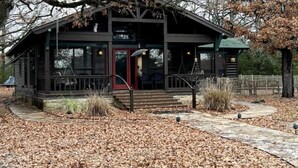 Un bâtiment de style rustique, semblable à un chalet, doté d’un porche, d’une porte rouge et d’un chemin de pierre menant à l’entrée.