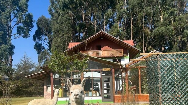 A building with a red roof and a balcony, surrounded by trees and grass. - RESORT ALAPA (San Jerónimo de Tunán)