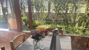 A table set with a teapot, cups, a pitcher, and a vase with flowers, overlooking a garden. - RESORT ALAPA (San Jerónimo de Tunán)
