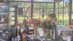 A covered dining area with a view of a green landscape. Tables are set with flowers and various dishes. - RESORT ALAPA (San Jerónimo de Tunán)
