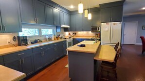 Een moderne keuken met donkerblauwe kastjes, een centraal kookeiland, een magnetron en een koelkast.