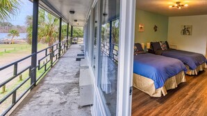 Una habitación con dos camas, un balcón con barandilla y vista al agua.