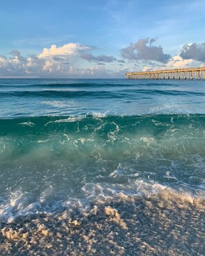 A beach with clear water, waves, and a pier in the distance. - Relax with your family or friends at this peaceful place to stay . (Navarre)
