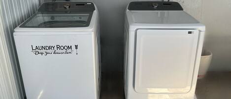 Two white laundry machines with a label that reads 'Laundry Room Drop your drawers here' on the left machine.
