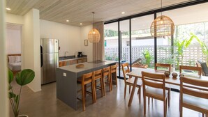 A modern kitchen with a central island, wooden chairs, and a dining table. - Villa Arlen - Brand new - Pool - Spacious (Mal País de Cobano)