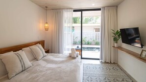 A bedroom with a bed, a TV, a plant, and a view of a pool and greenery. - Villa Arlen - Brand new - Pool - Spacious (Mal País de Cobano)
