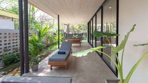 A covered outdoor area with two lounge chairs, a concrete floor, and potted plants. - Villa Arlen - Brand new - Pool - Spacious (Mal País de Cobano)