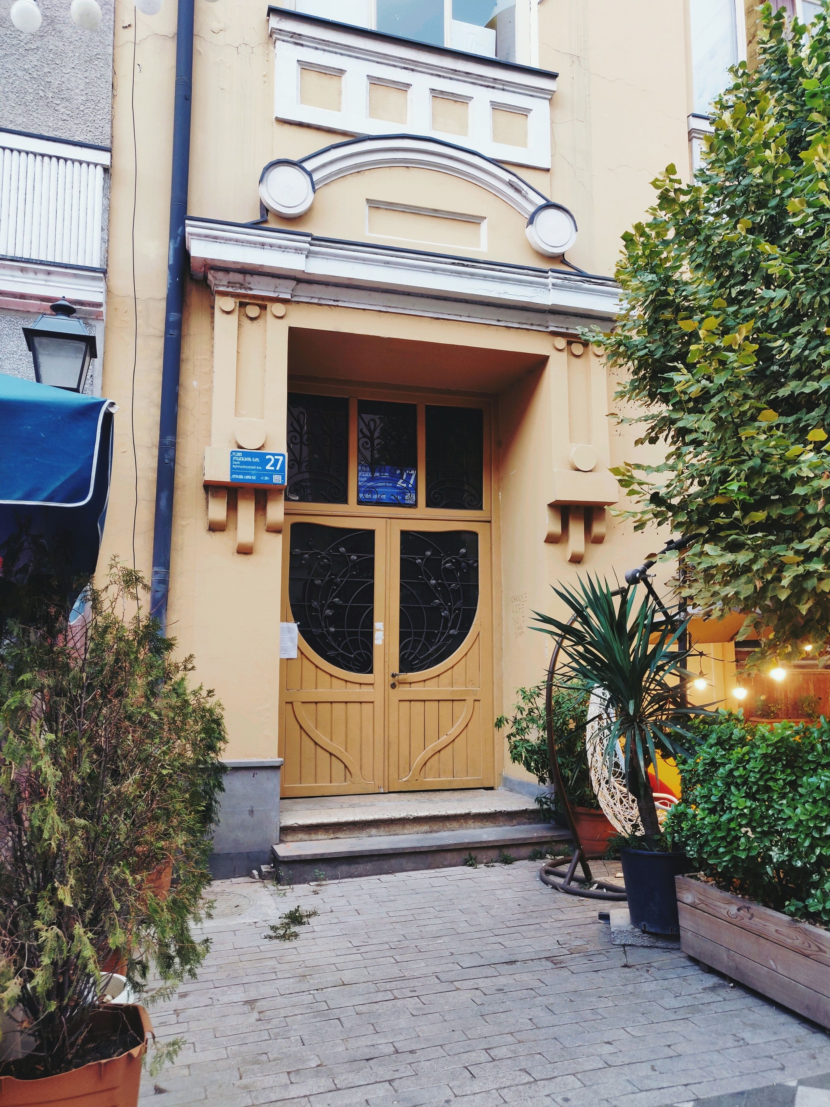 A building with a large wooden door, a balcony, and a sign with the number 27.