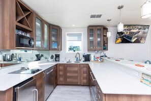 A modern kitchen with wooden cabinets, a large island, and a window.