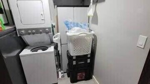Een kleine wasruimte met een wasmachine, een droger en een stapelbare wasmand.