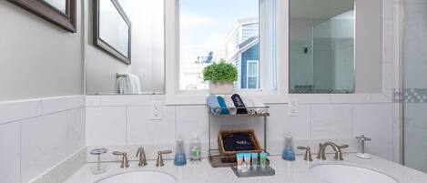Un baño moderno con dos lavamanos, un espejo grande y una ventana con vistas a edificios.
