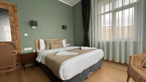 Ein Schlafzimmer mit Bett, Nachttisch, Stuhl und einem Fenster mit Vorhängen.