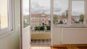 Ein Zimmer mit großem Fenster, Heizkörper und Balkon mit Blumentöpfen.