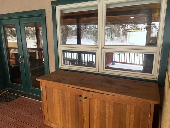 Ein Holzschrank mit Glastür, eine hölzerne Bank und ein Fenster mit Blick auf eine verschneite Landschaft.