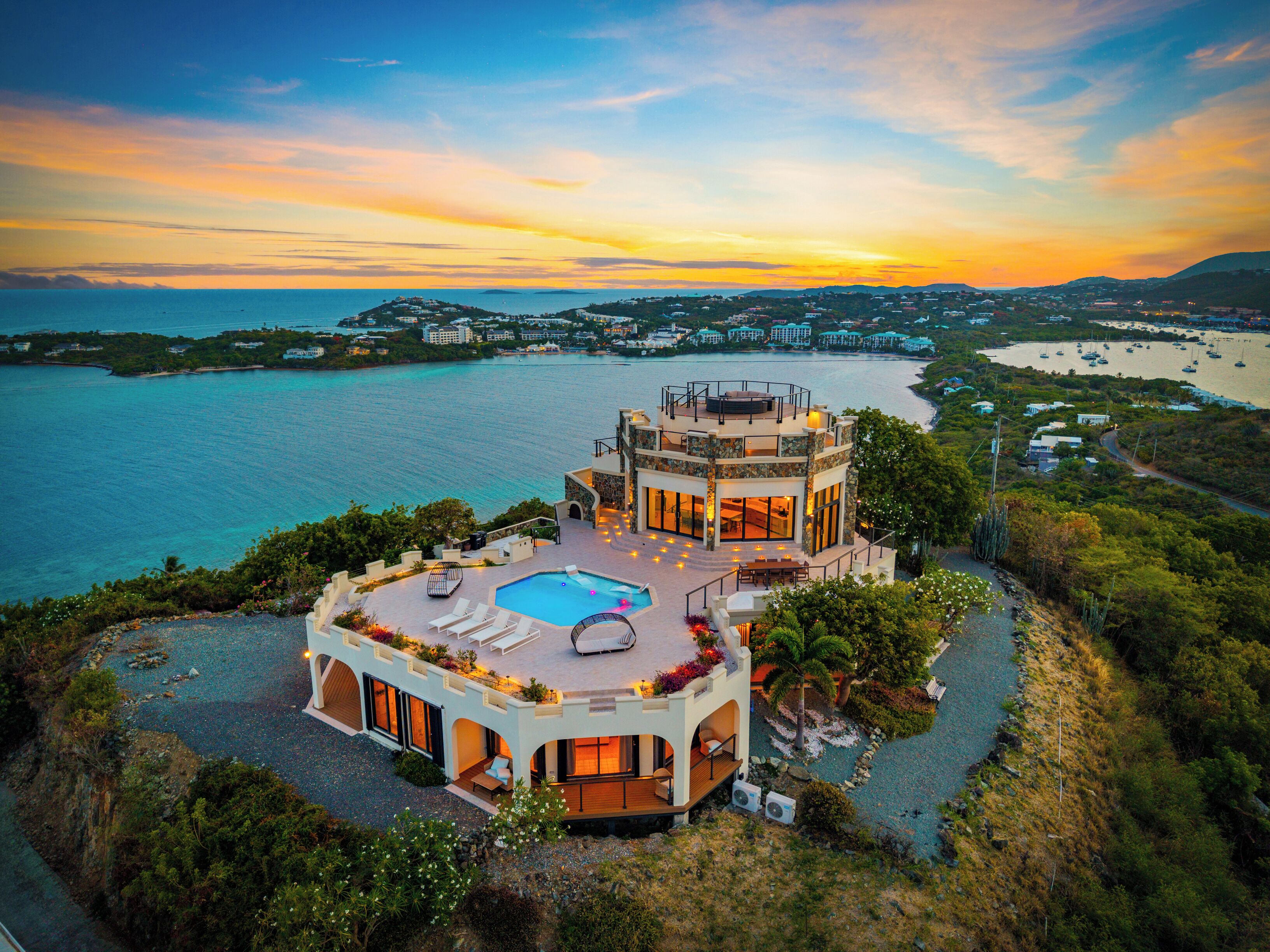 A two-story building with a rooftop pool and a view of the sea.