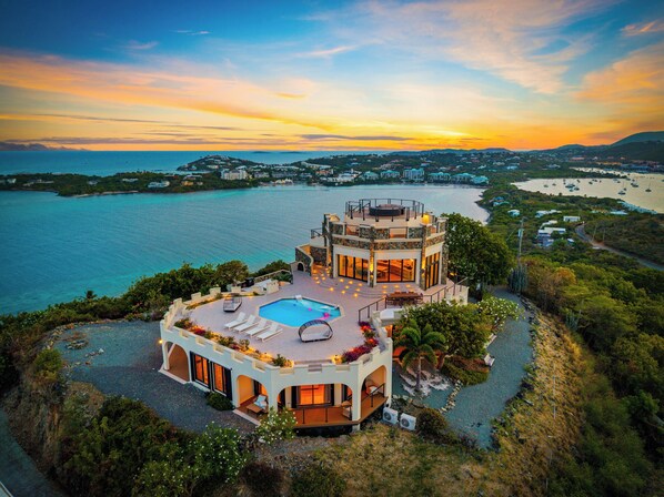 A two-story building with a rooftop pool and a view of the sea.