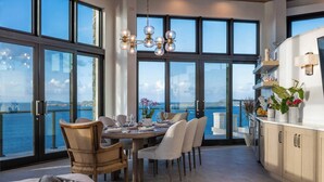 A dining area with a view of the sea, large windows, and a modern chandelier.