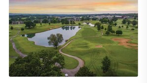 A golf course with a pond, surrounded by trees and buildings. - Gated, Luxe Mid-Century Modern Condo| Walk to golf & pools! (Branson)