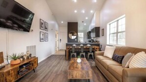 A modern living room with a wooden coffee table, a beige sofa, and a TV mounted on the wall. - Gated, Luxe Mid-Century Modern Condo| Walk to golf & pools! (Branson)