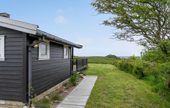 A dark wooden house with a porch and a pathway leading to a grassy area. - Stunning home in Vestervig with kitchen (Vestervig)