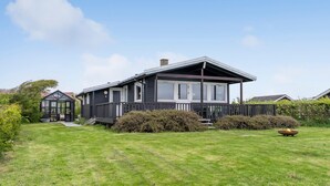 A two-story house with a large front porch, a conservatory, and a well-maintained lawn. - Stunning home in Vestervig with kitchen (Vestervig)