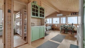 A cozy cabin interior with bunk beds, a kitchenette, a dining area, and large windows offering a view. - Stunning home in Vestervig with kitchen (Vestervig)