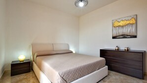 Ein Schlafzimmer mit einem Bett, einem Schminktisch, einem Nachttisch und einer Wandlampe.