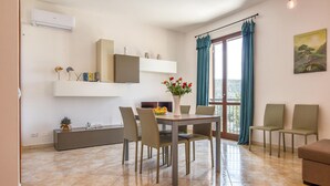Ein modernes Wohnzimmer mit Essbereich, einer Couch, einem Fernseher und Blick ins Freie.