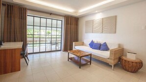 A modern living room with a sofa, coffee table, and a dining area with a counter and chairs. - Golden Sands Destination Resorts (Cebu Island)