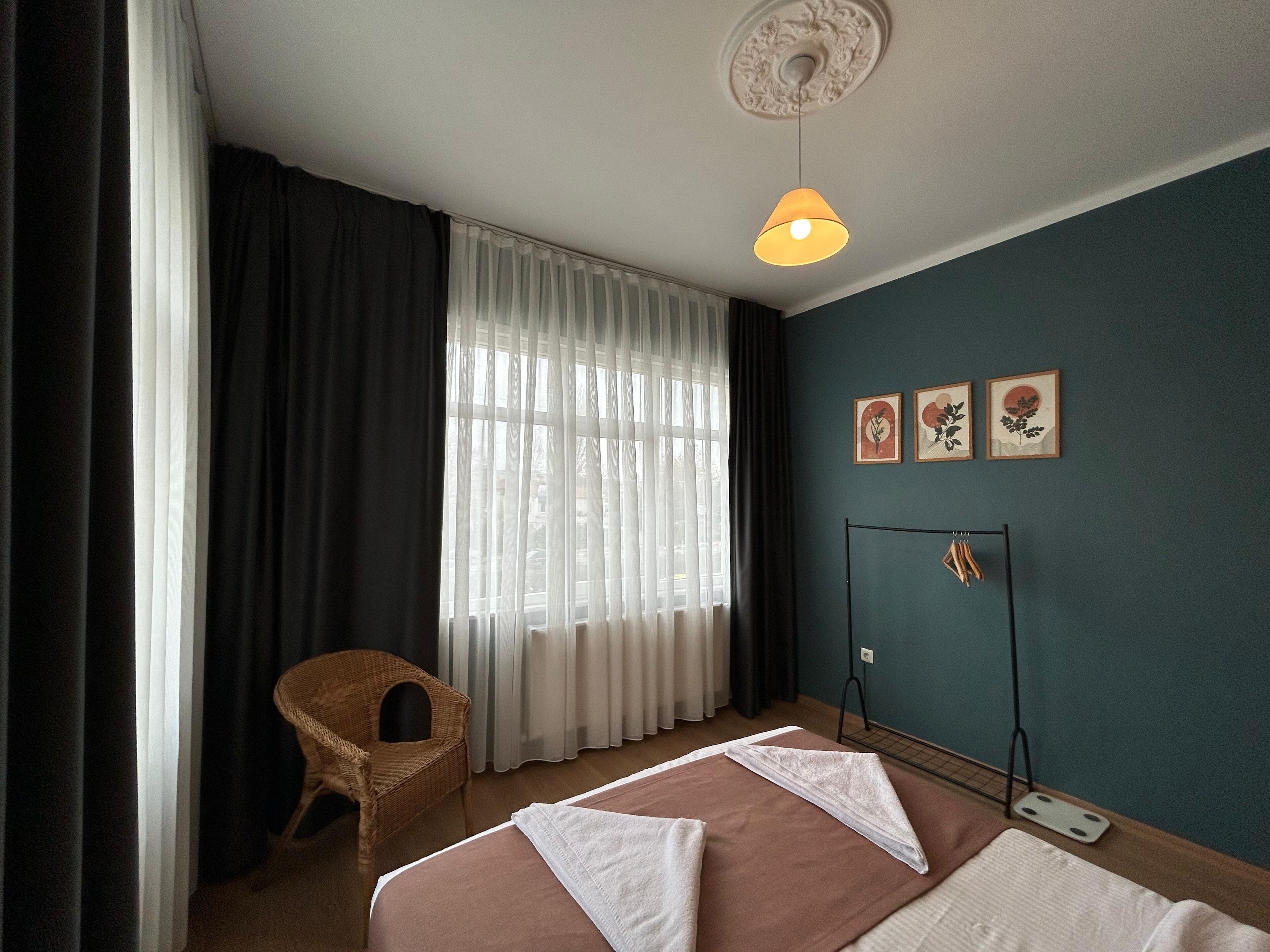 Una habitación de hotel con una cama, una silla, una ventana con cortinas y decoración en la pared.