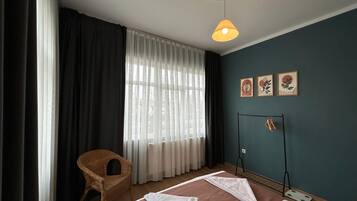 Una habitación de hotel con una cama, una silla, una ventana con cortinas y decoración en la pared.