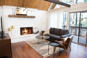 Cozy up by the fireplace in this inviting living room, featuring a comfortable sofa and a stunning view through the large glass door.