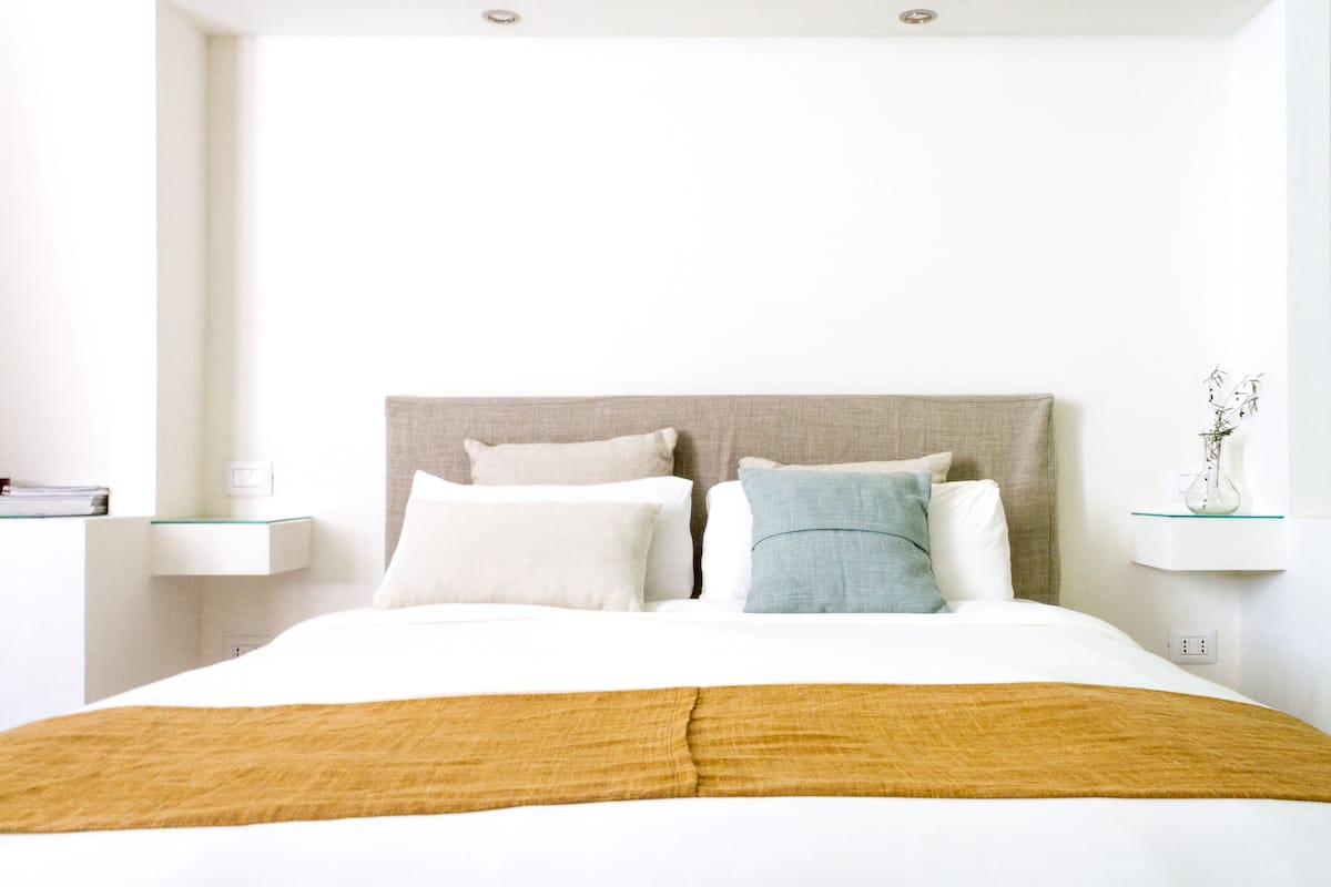 Een moderne hotelkamer met een groot bed, witte beddengoed en een neutraal kleurenpalet.