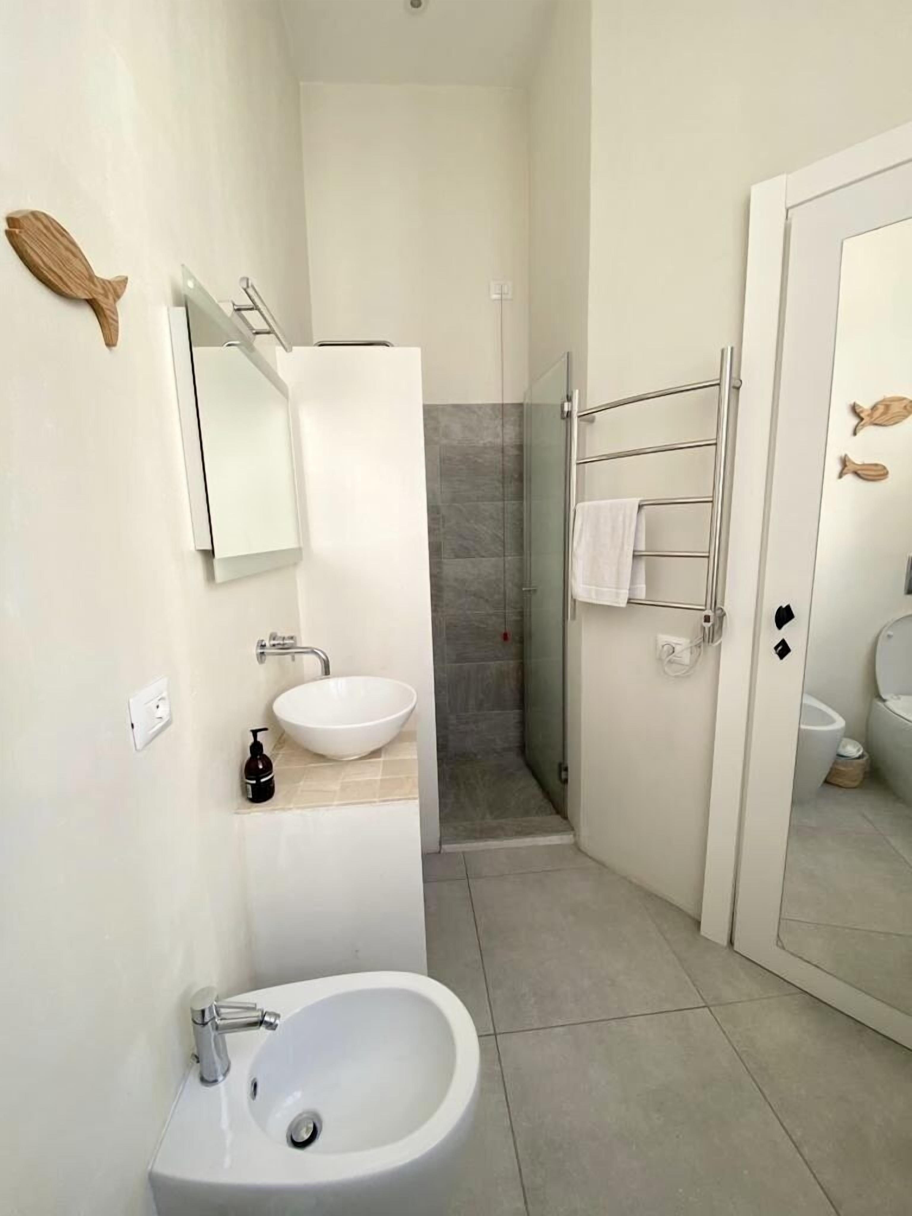 A modern bathroom with a white sink, a glass shower enclosure, and a toilet.