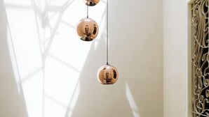 A room with a black metal crib, a window with decorative metal bars, and three hanging spherical light fixtures. - Fra Cielo e Mare (Cagliari)