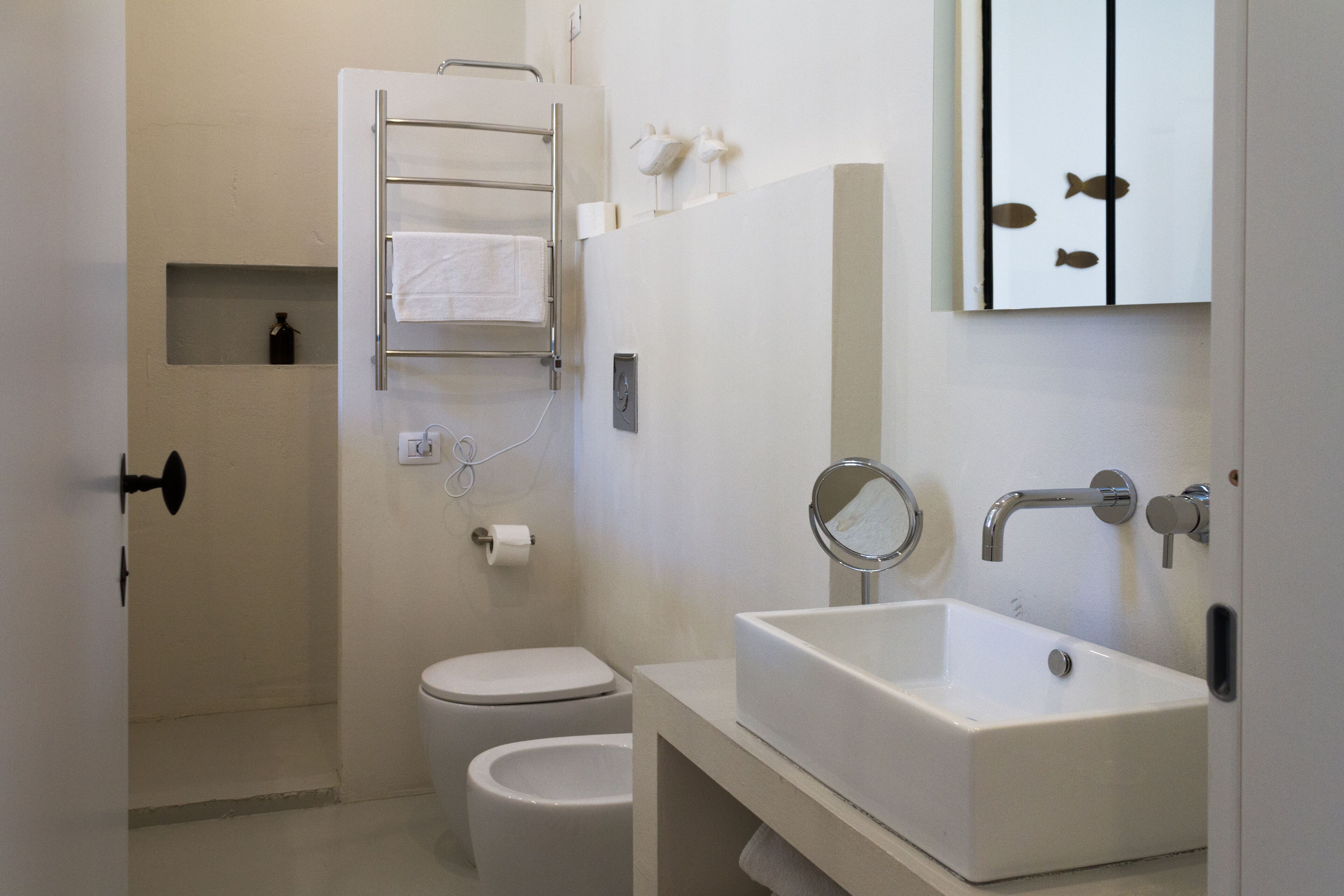 Uma casa de banho moderna com sanita, bidé e uma grande pia com espelho.