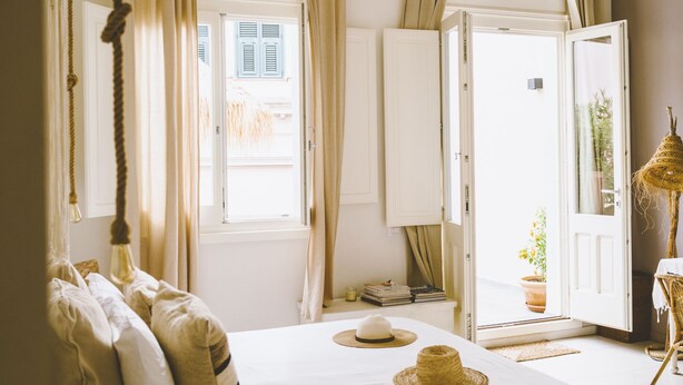 A bedroom with a bed, curtains, a window, and a door. - Fra Cielo e Mare (Cagliari)